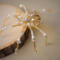 Golden beaded spider with warm metallic tones, pearl accents, and a clear glass bead body designed as a unique decorative ornament.